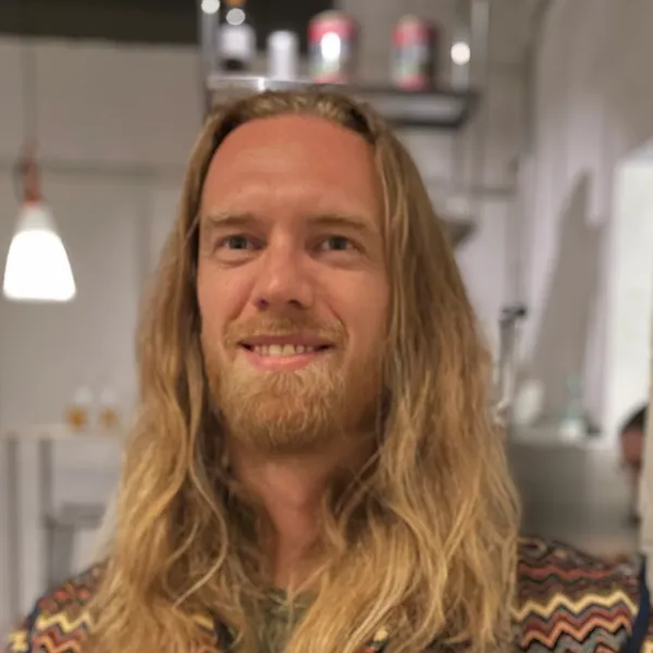 Hannes, smiling, in a patterned zigzag jacket against a white wall.