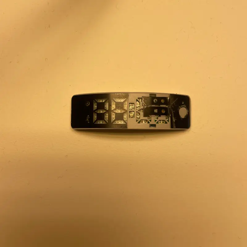 A bare circuit board for the band, its components lit warm against a cream ground.