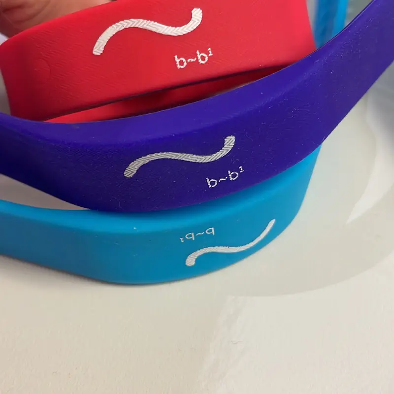 Three silicone bands in red, purple and blue, each with the same white wave mark.