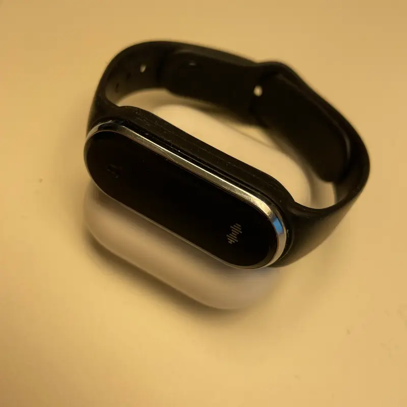 A black band with a glossy dark capsule face, photographed on a cream ground.