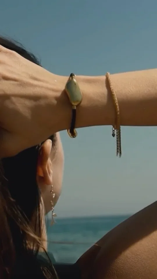 Someone by the sea pushing their hair back, wearing the Sou band